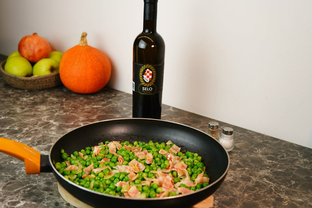 Savory French Peas with Bacon (Grašak sa Slaninom) drizzled with Croatian olive oil, served in a bowl with crispy bacon pieces and garnished with fresh herbs, offering a delicious and comforting side dish.