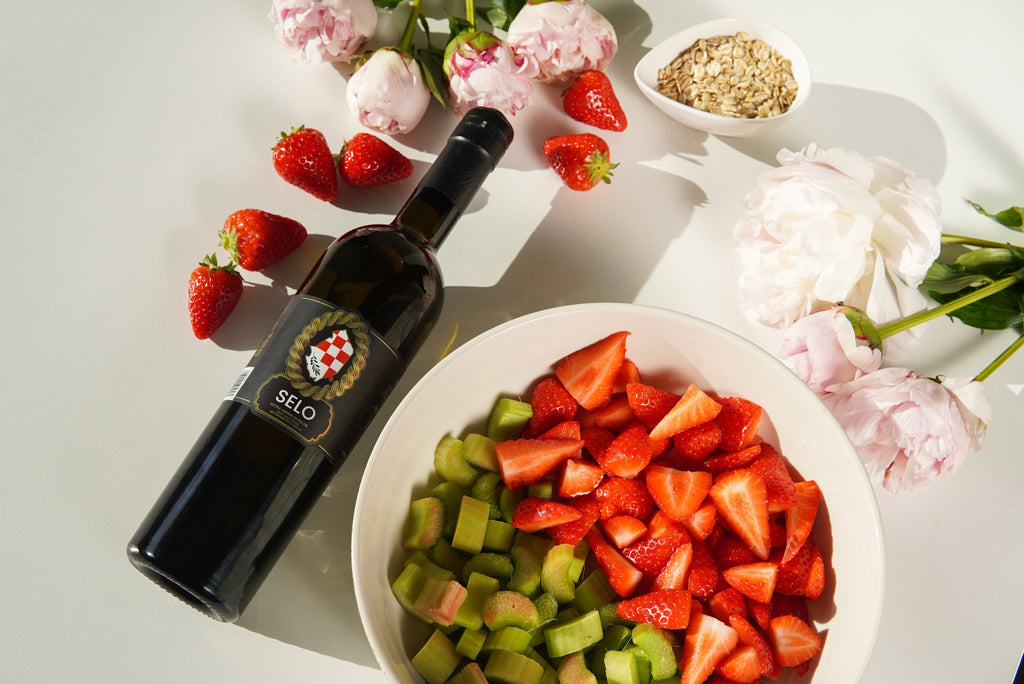 Craft Selo Croatian olive oil alongside vibrant flowers, strawberries, and rhubarb.