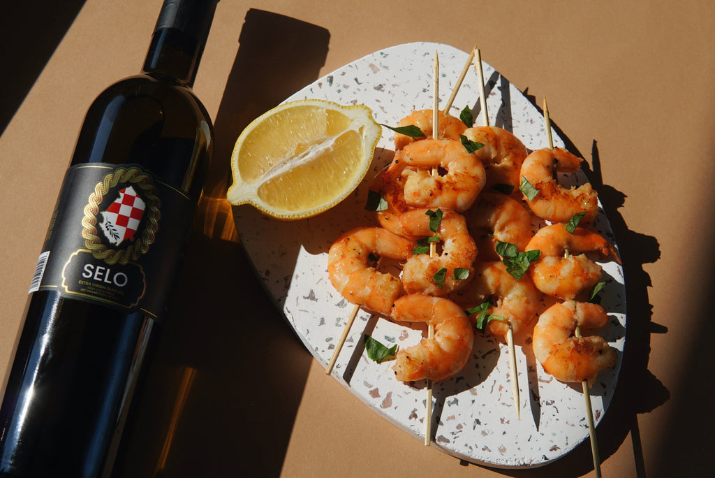 Grilled Chili Shrimp on skewers garnished with fresh cilantro and served with lime wedges on a rustic wooden table.