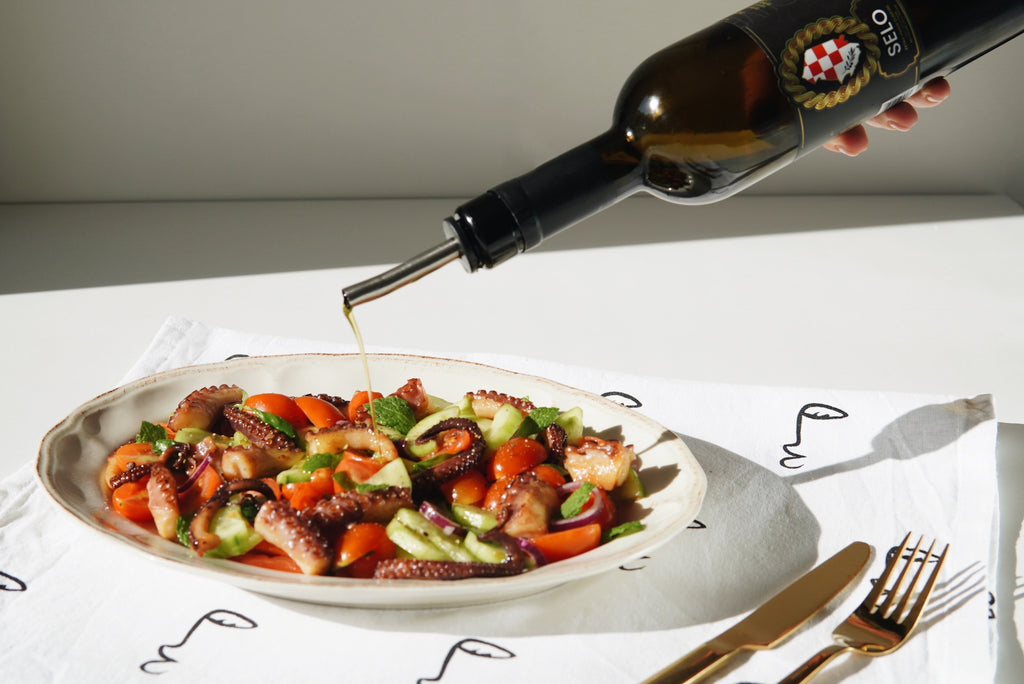 Selo Croatian olive oil rich in omega-3 being poured over a fresh octopus salad.