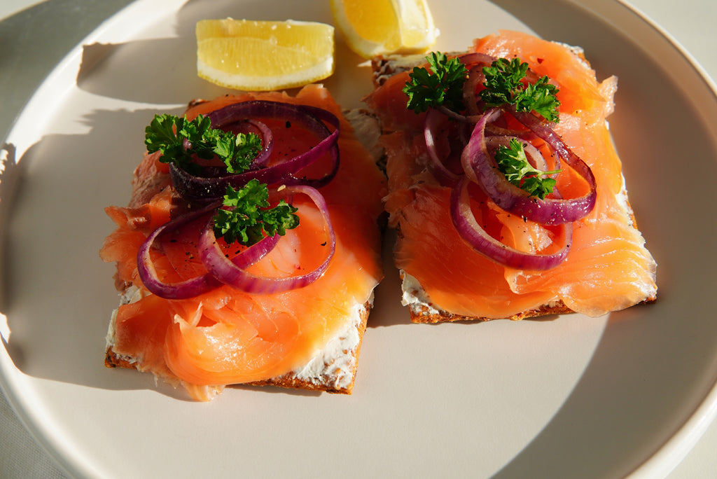 A delectable arrangement of smoked salmon on a cracker, adorned with red onion and accompanied by Croatian olive oil, showcasing a fusion of flavors and textures.