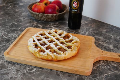 A slice of Olive Oil Apple & Cinnamon Pie on a white plate, showing layers of spiced apple filling and a drizzle of olive oil on top.